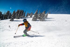 person in red jacket and blue pants skiing