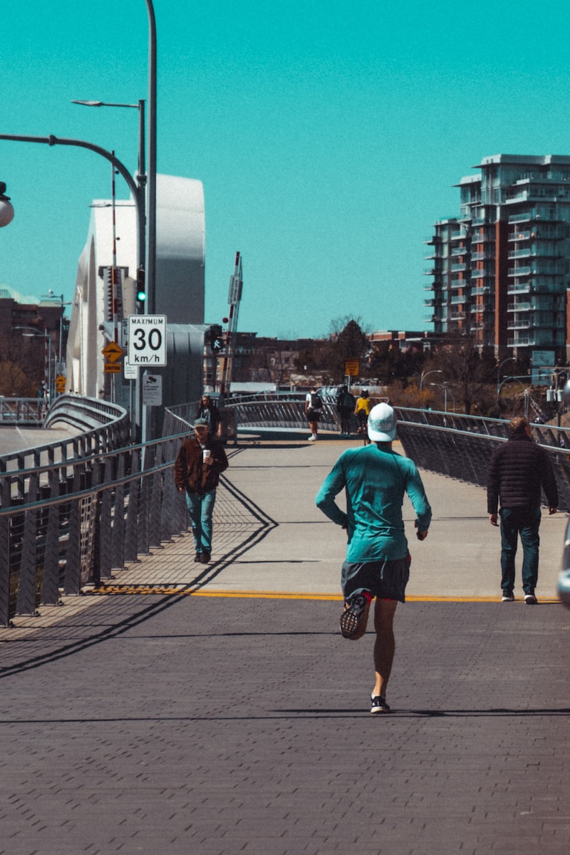 man in blue jacket and brown pants walking on sidewalk during daytime training for a marathon