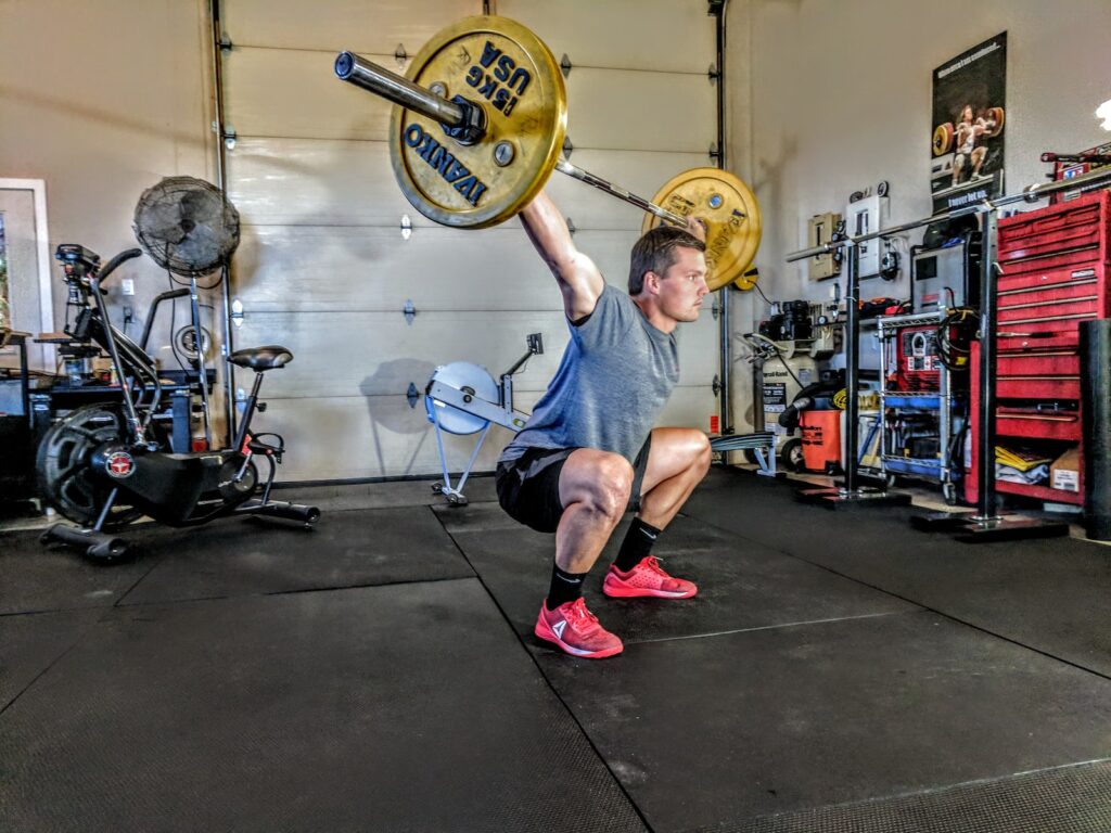 man in gray t-shirt lifting gray and yellow barbell