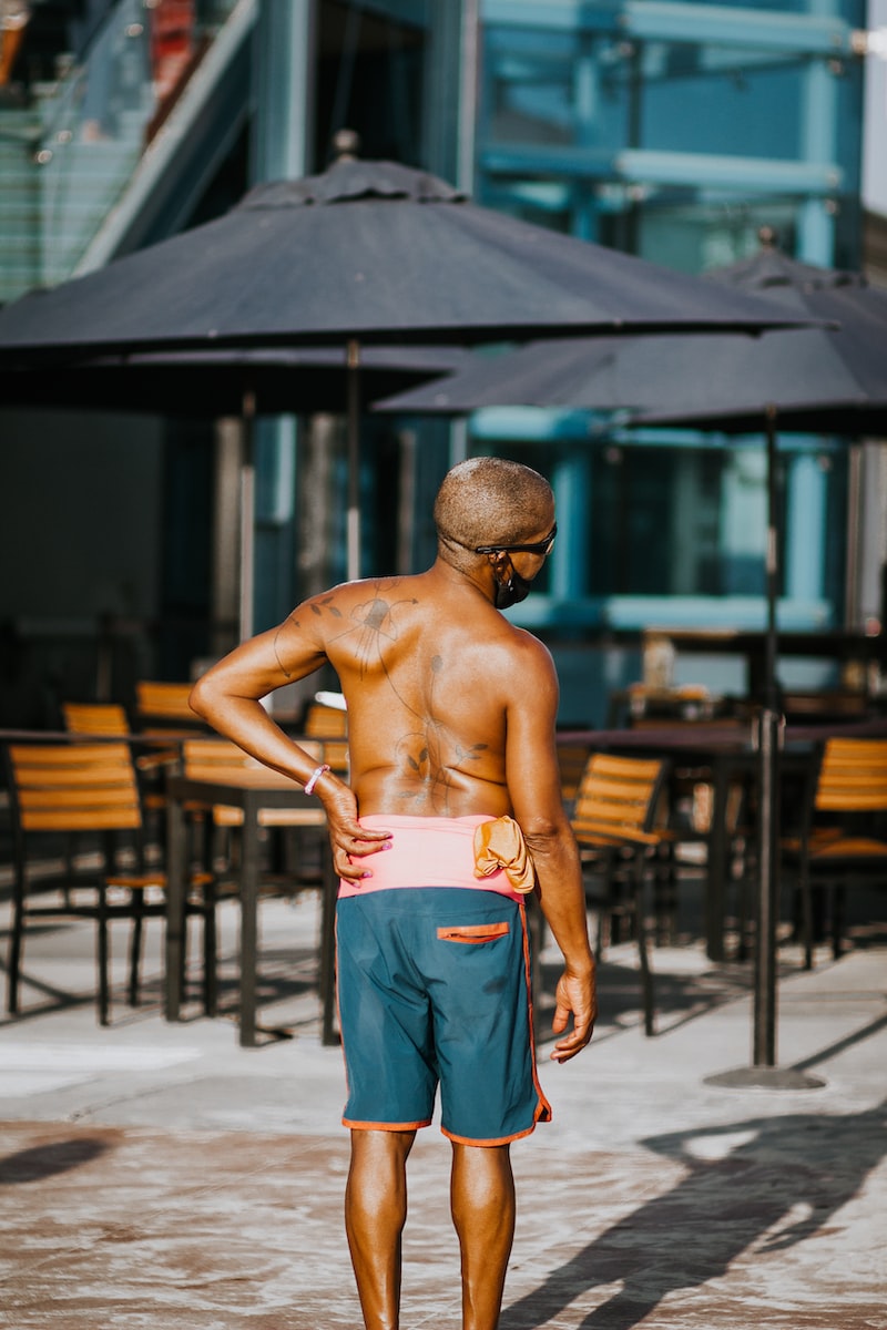 topless man in blue denim jeans standing near brown wooden table lower back pain