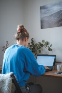 woman in blue sweater sitting in front of laptop computer posture lower back pain