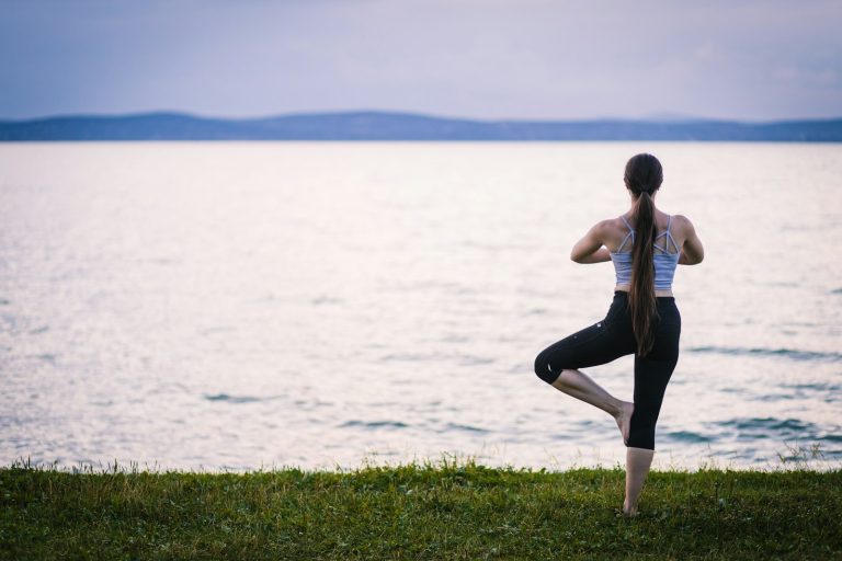 a woman is doing yoga by the water