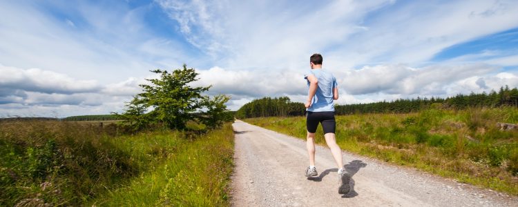 man running on road near grass field